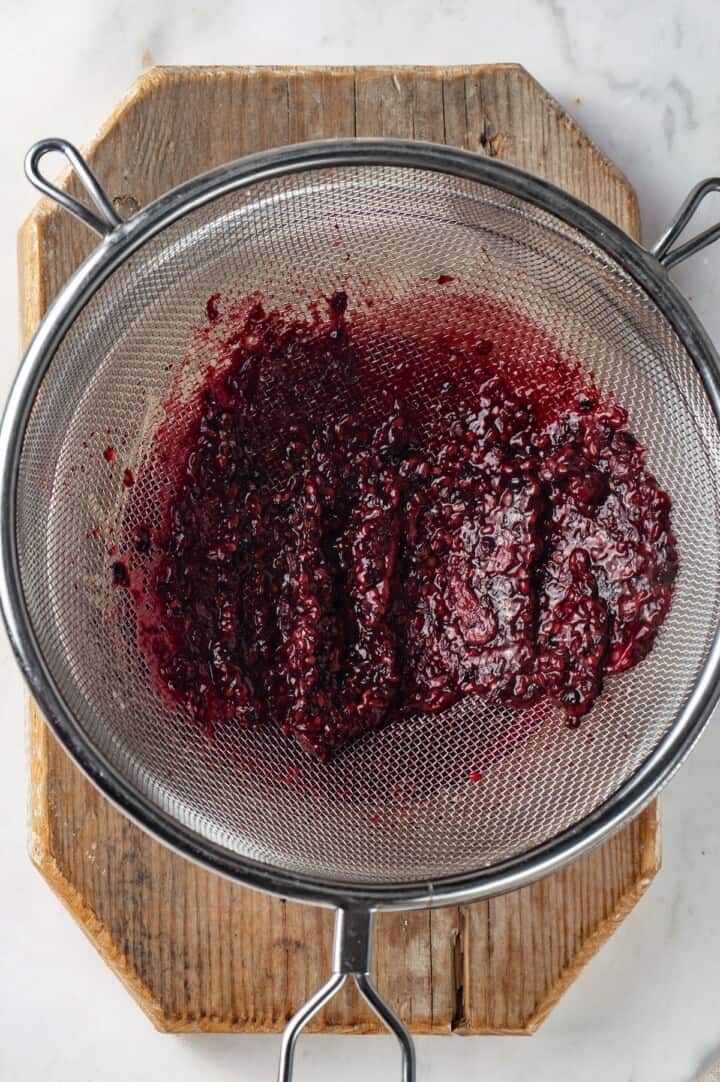 Overhead view of blackberry pulp in mesh strainer