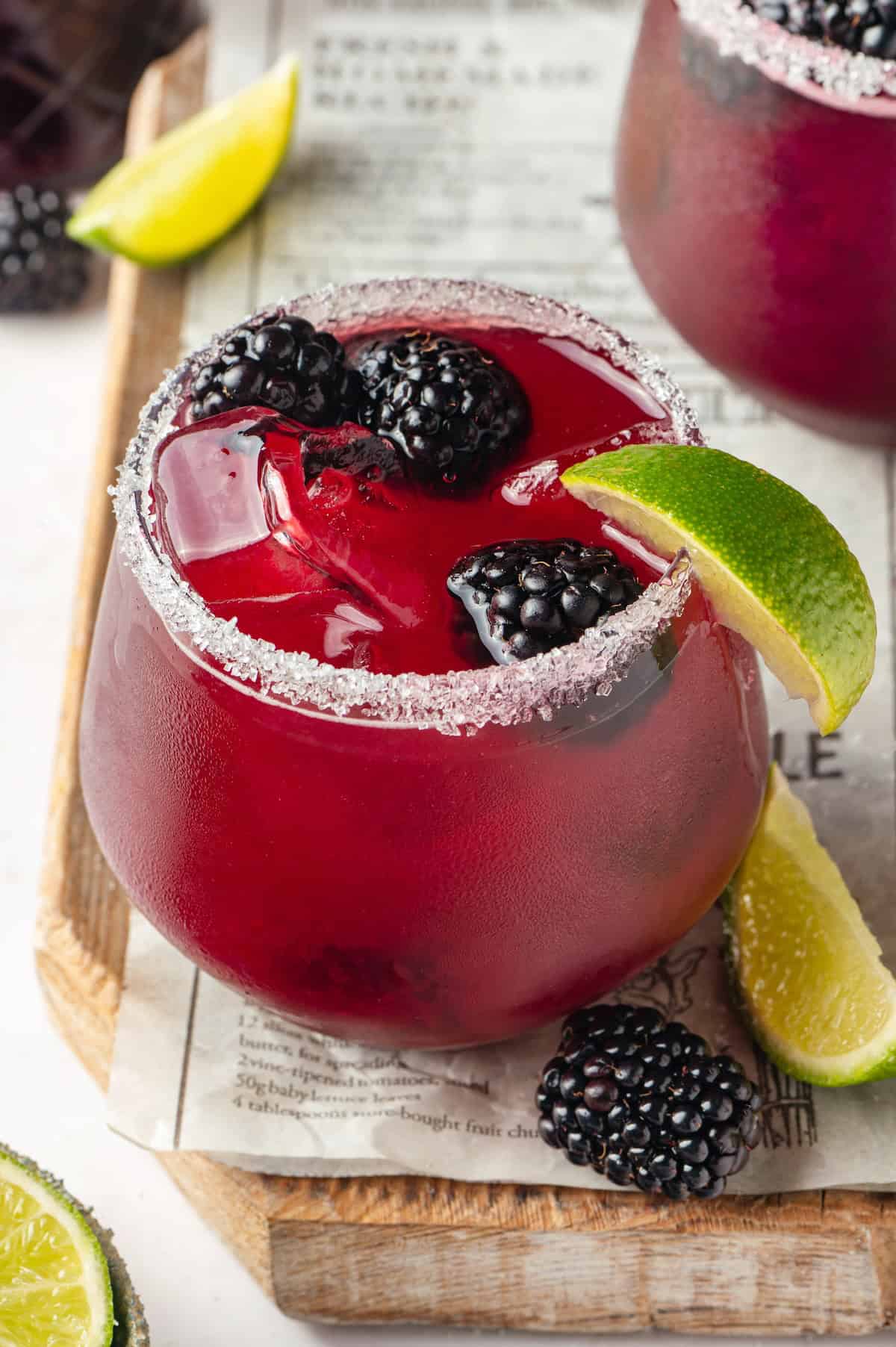 This summery blackberry margarita recipe is refreshing, delicious, and perfect for adding to your Taco Tuesday menu. It's always a hit! Salted glass with blackberry margarita and fresh berries for garnish