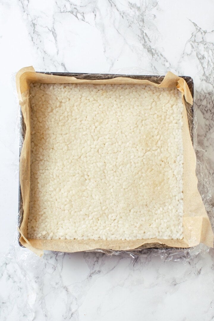 Sushi rice pressed into square baking dish