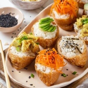 Vegan inari sushi topped with tofu, avocado, carrots, and nori