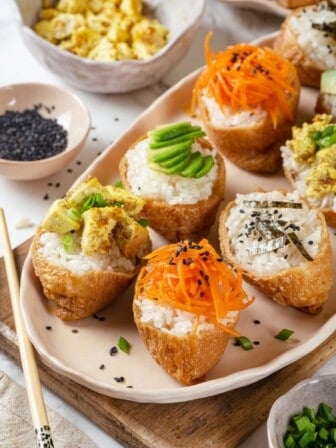 Vegan inari sushi topped with tofu, avocado, carrots, and nori