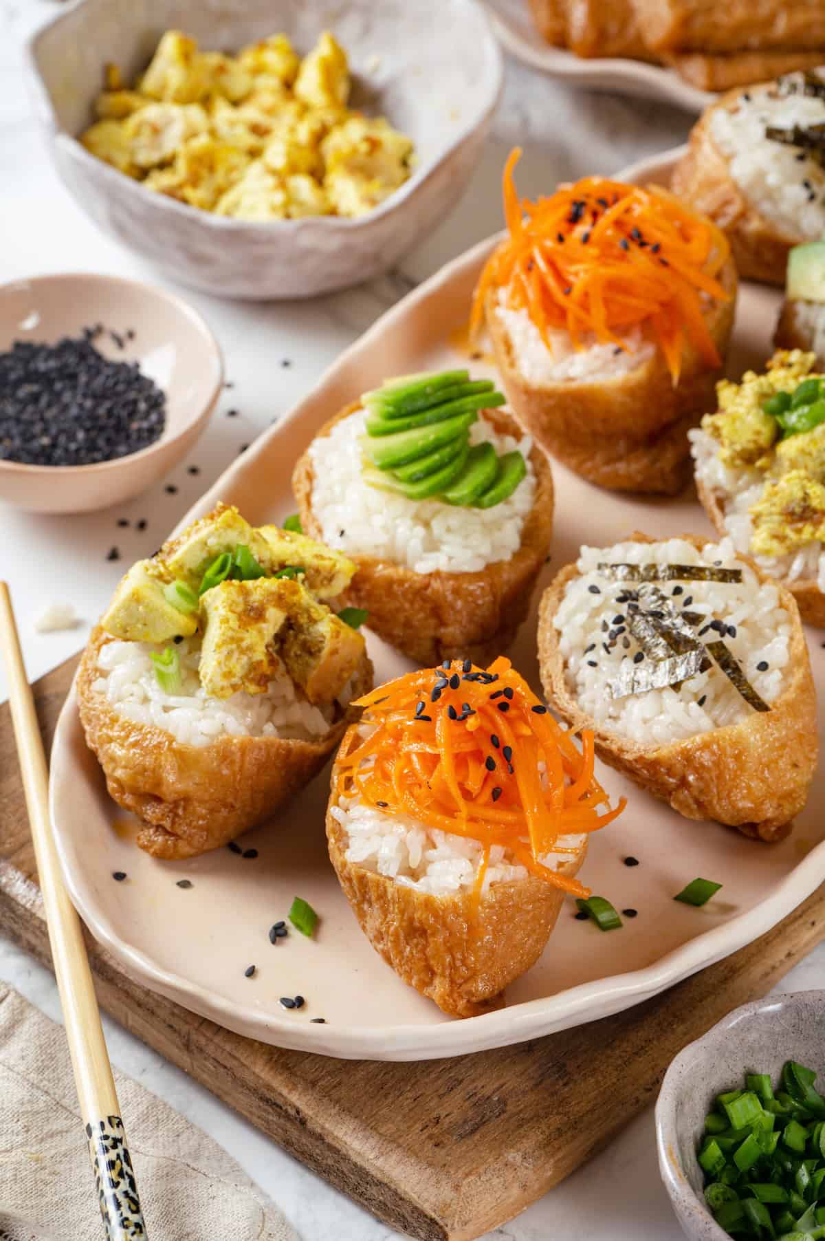 Vegan inari sushi topped with tofu, avocado, carrots, and nori