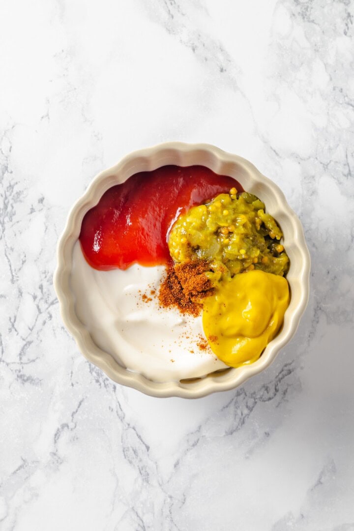 This easy burger sauce is made with pantry staples, which means you can mix it up anytime you need it for burgers, fries, wings and more! Overhead view of ingredients for burger sauce in bowl before stirring