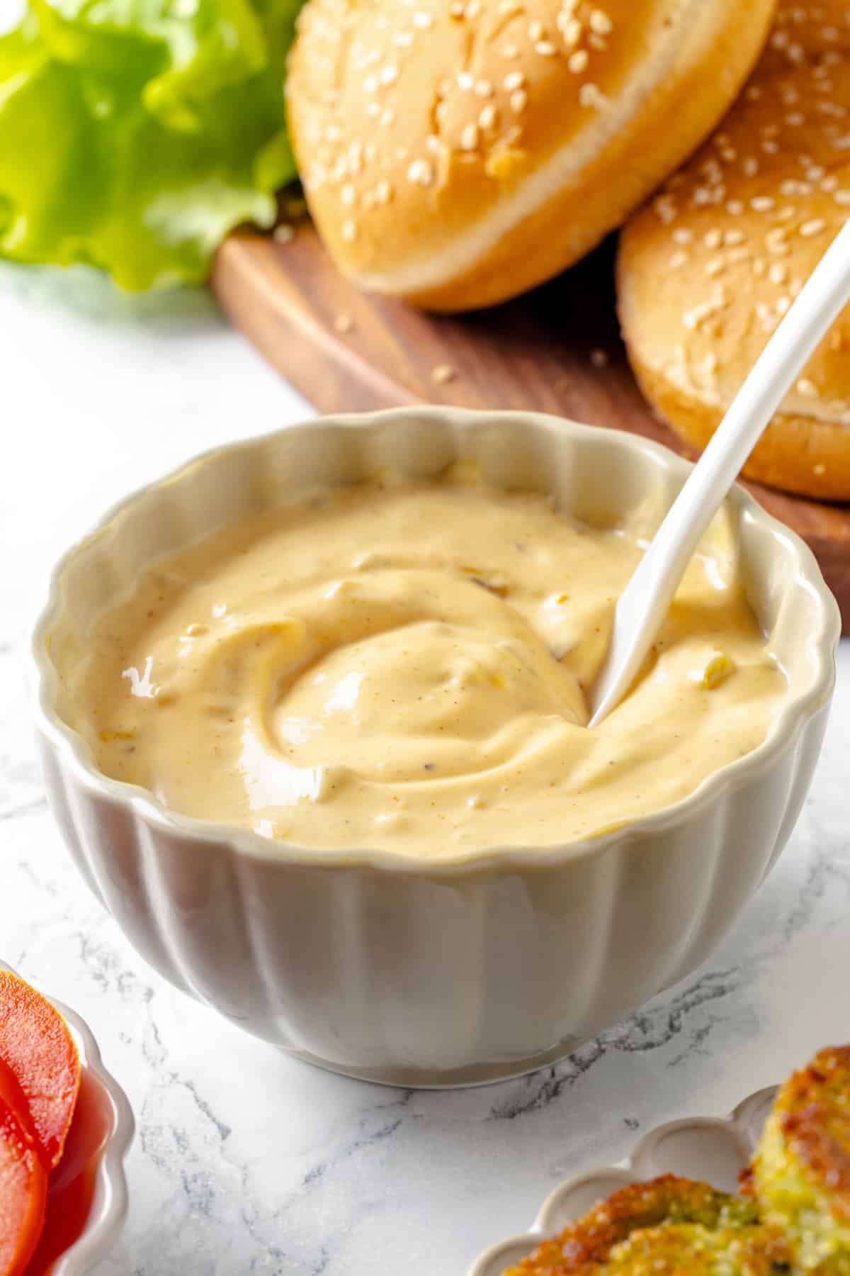 This easy burger sauce is made with pantry staples, which means you can mix it up anytime you need it for burgers, fries, wings and more! Bowl of vegan burger sauce with spoon