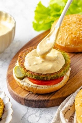 Spooning burger sauce onto vegan burger