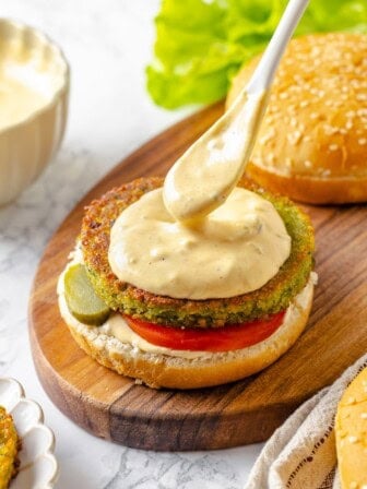 Spooning burger sauce onto vegan burger