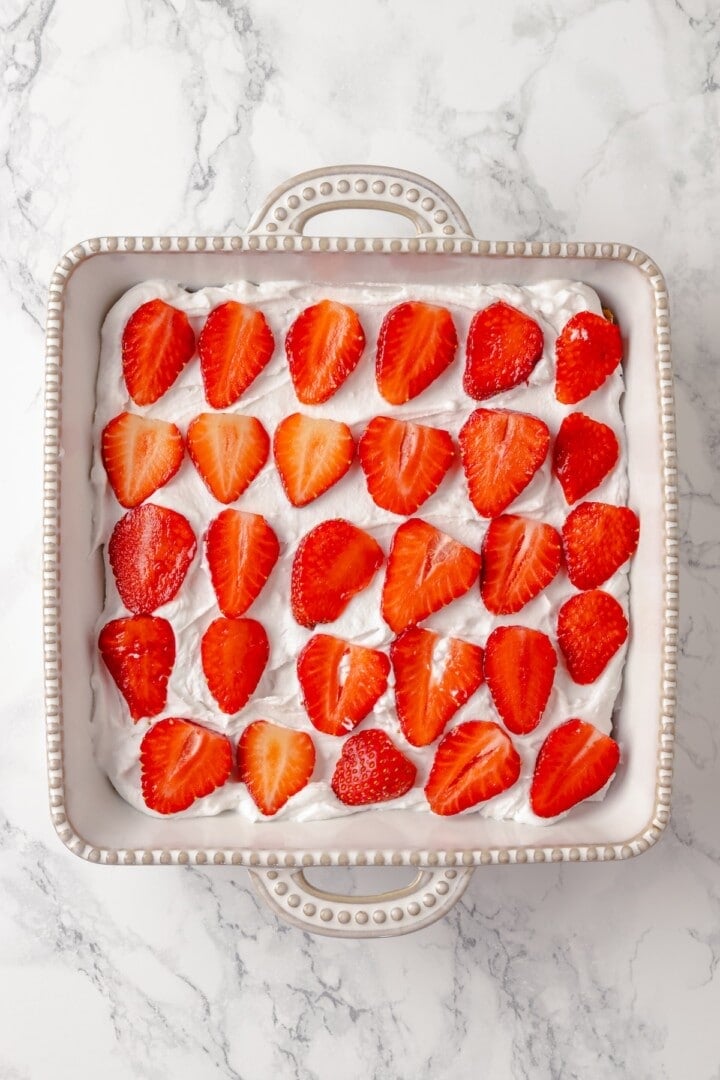Whipped cream and strawberries layered in dish for icebox cake
