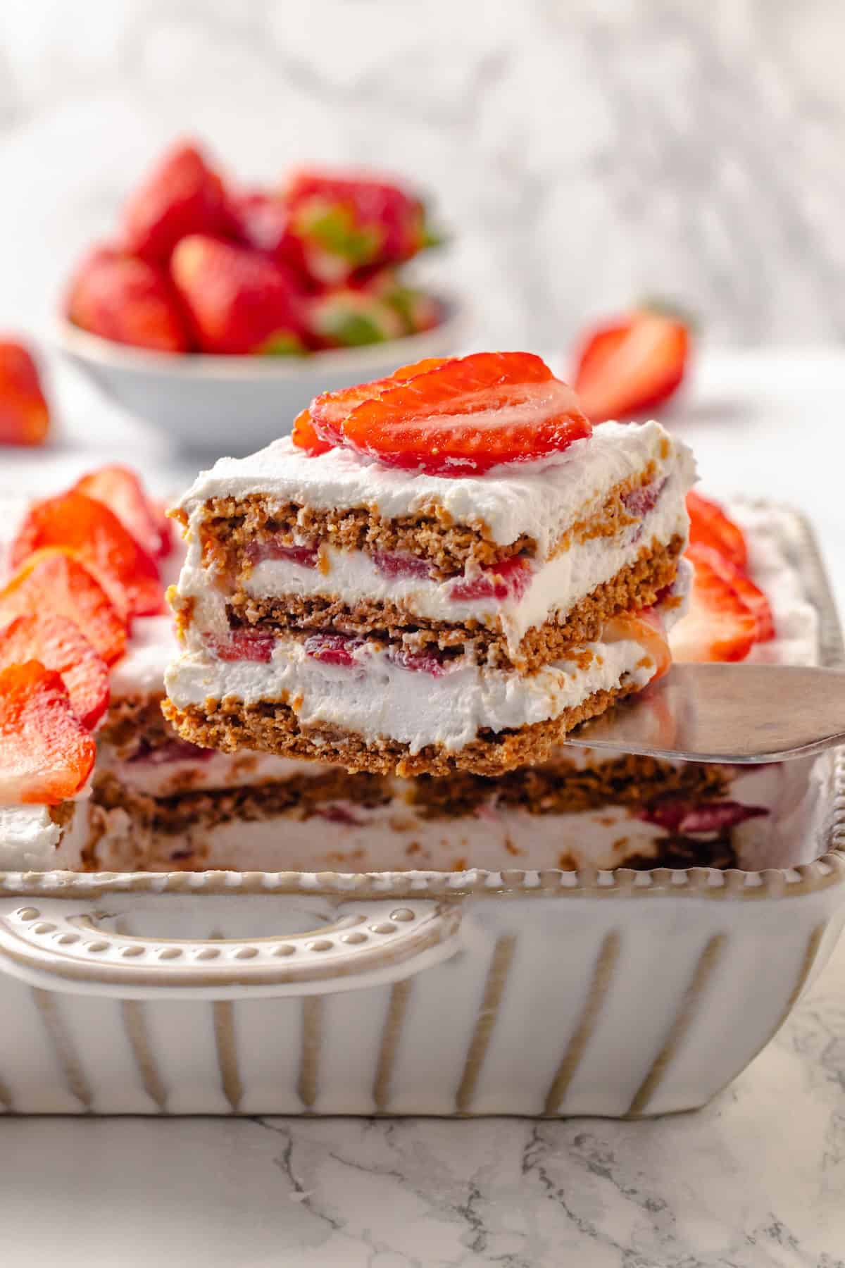 Lifting slice of strawberry icebox cake from dish