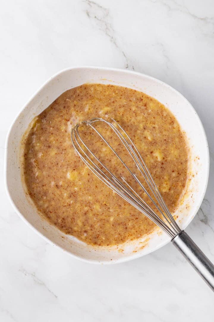 Overhead view of wet ingredients in mixing bowl with whisk