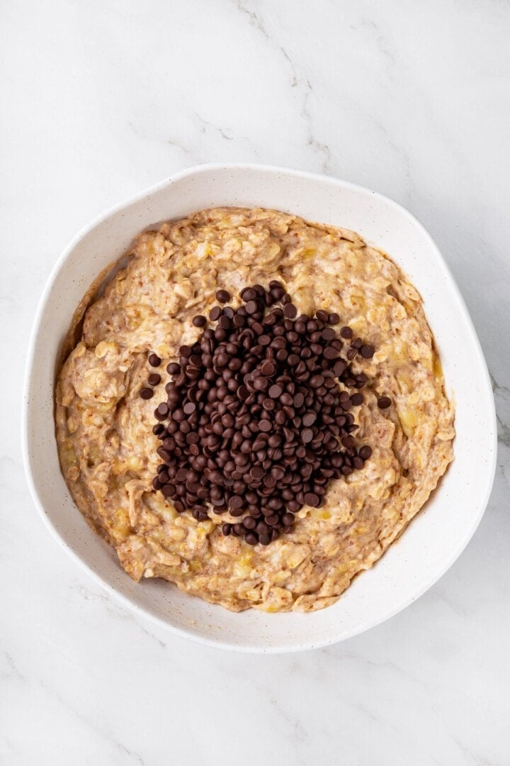 Overhead view of chocolate chips added to bowl of batter