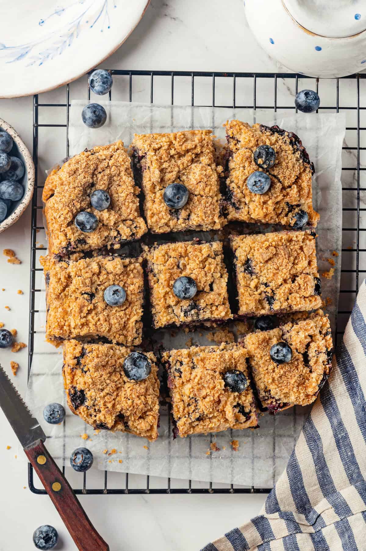 Overhead view of sliced blueberry buckle on parchment-covered wire rack
