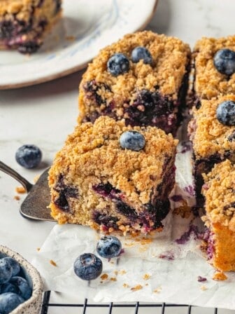Spatula pulling blueberry buckle from wire rack