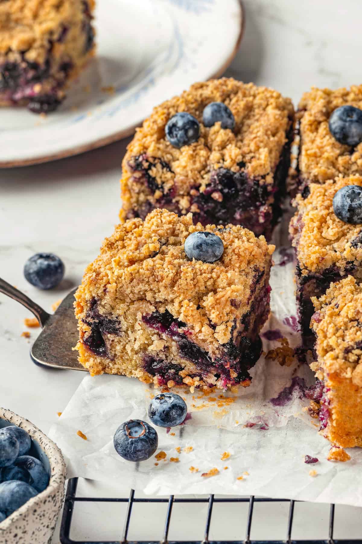 Spatula pulling blueberry buckle from wire rack