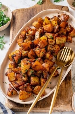 Crispy breakfast potatoes on platter with serving spoon and fork