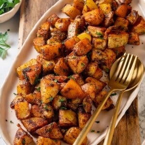 Crispy breakfast potatoes on platter with serving spoon and fork