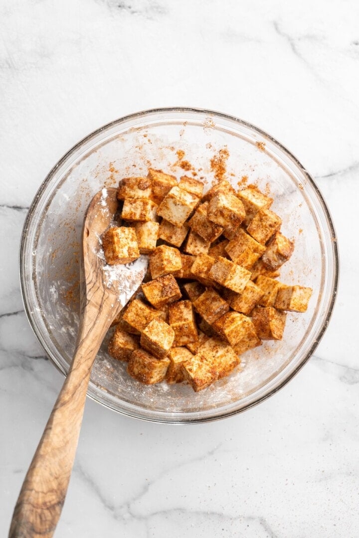 Overhead view of tofu with seasonings in bowl