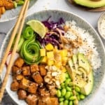 Overhead view of peanut tofu bowl with mango, edamame, avocado, and rice
