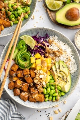 Overhead view of peanut tofu bowl with mango, edamame, avocado, and rice