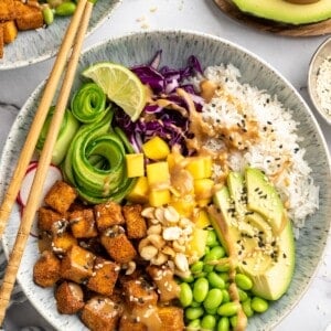 Overhead view of peanut tofu bowl with mango, edamame, avocado, and rice