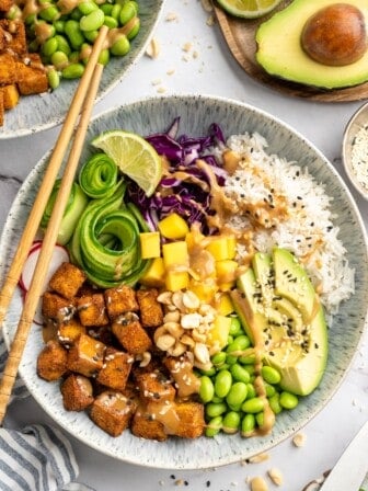 Overhead view of peanut tofu bowl with mango, edamame, avocado, and rice