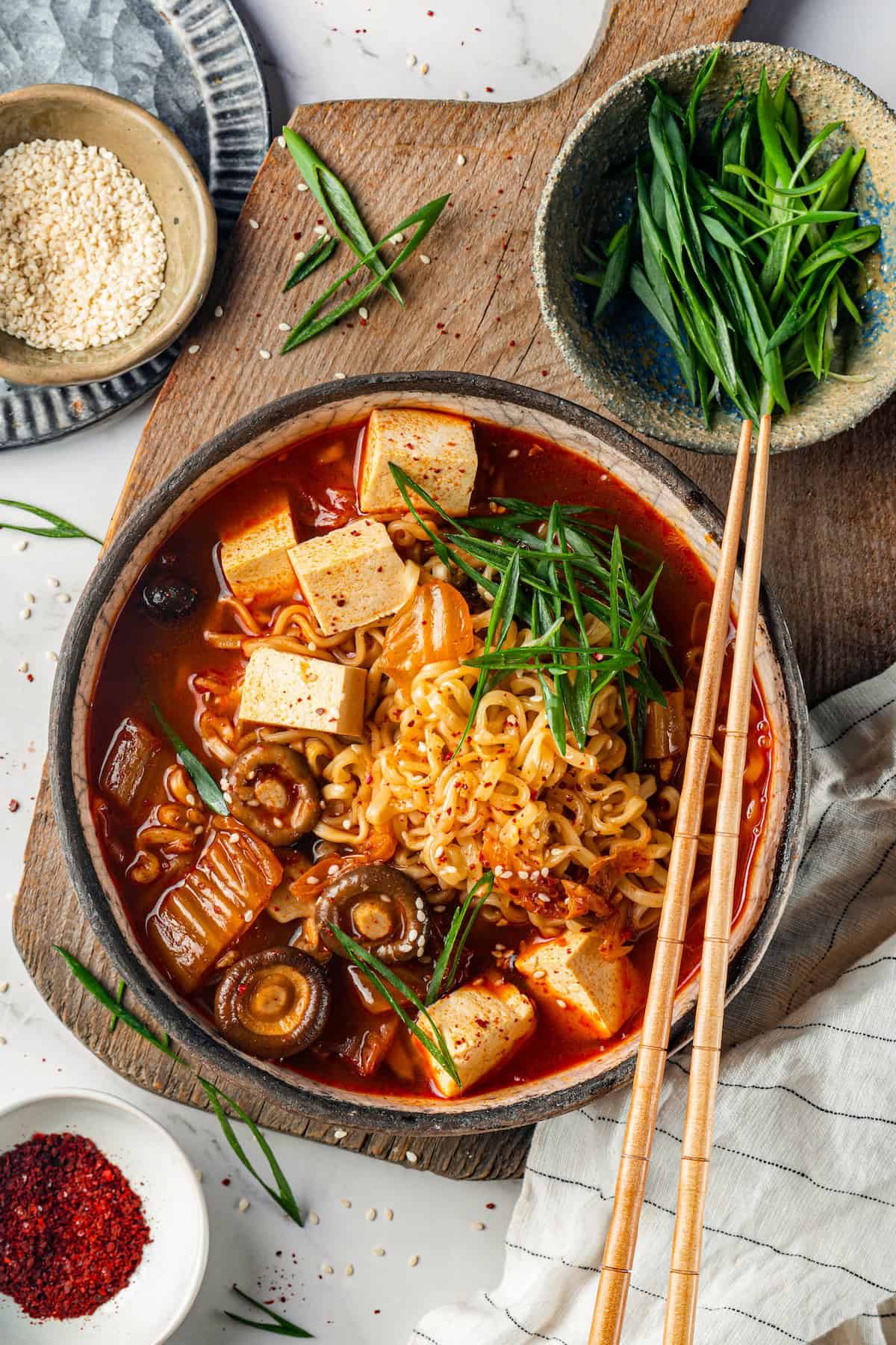 Overhead view of kimchi ramen in bowl with small bowl of sliced green onions