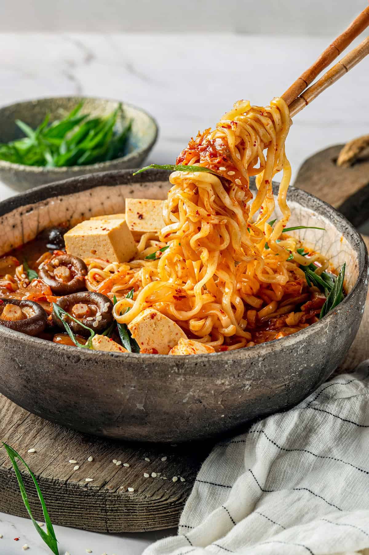 Chopsticks lifting kimchi ramen from bowl