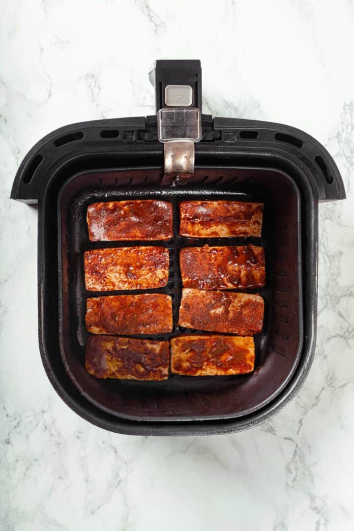 Overhead view of sliced tofu cooking in air fryer