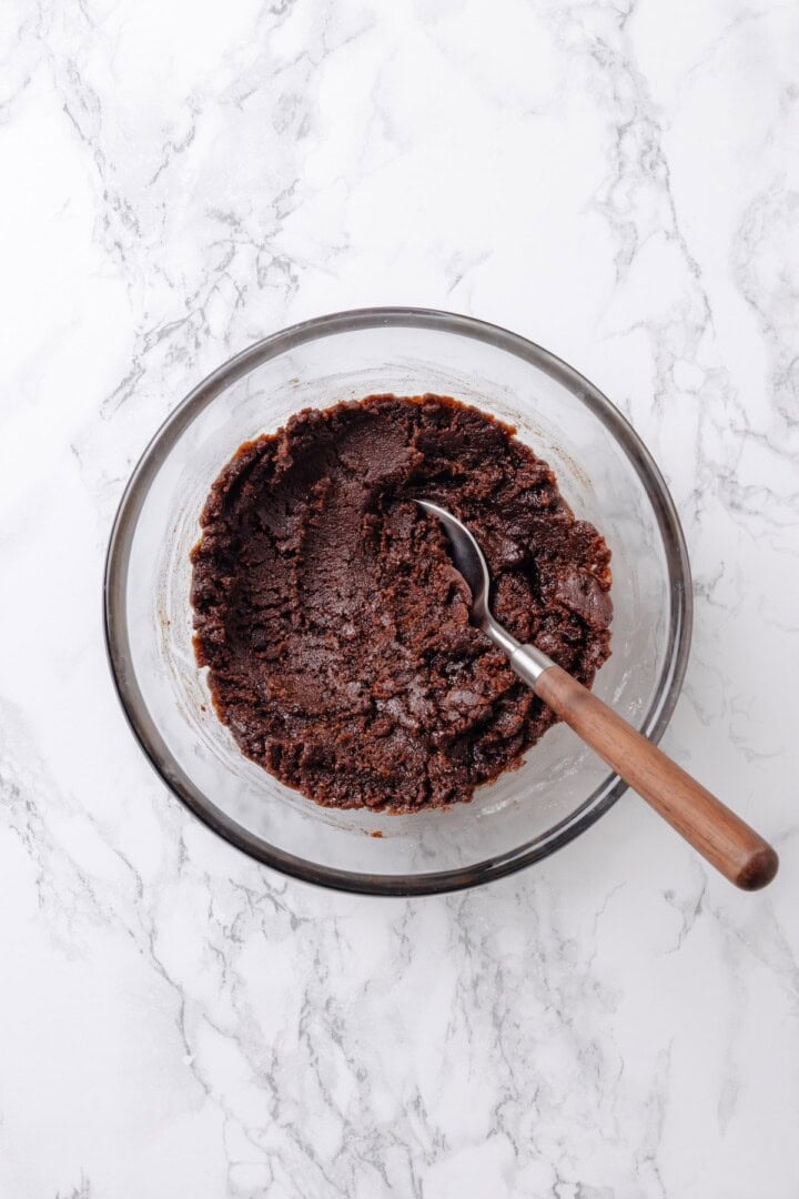 With a brown sugar cinnamon swirl and cream cheese frosting, this cinnamon roll cheesecake recipe is cozy and decadent at the same time! Overhead view of cinnamon swirl mixture in bowl with spoon