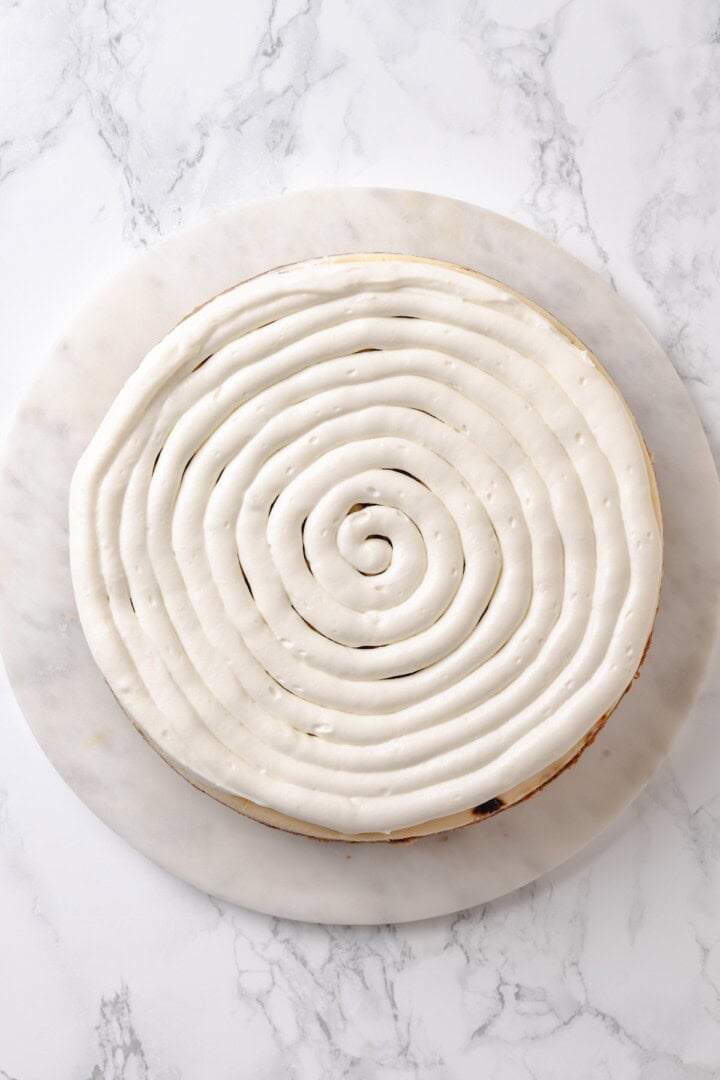 With a brown sugar cinnamon swirl and cream cheese frosting, this cinnamon roll cheesecake recipe is cozy and decadent at the same time! Cream cheese frosting piped onto cinnamon roll cheesecake
