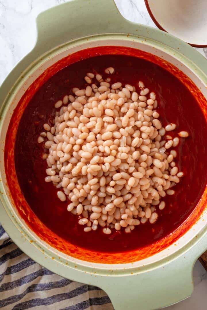 Overhead view of cooked beans added to pot of sauce