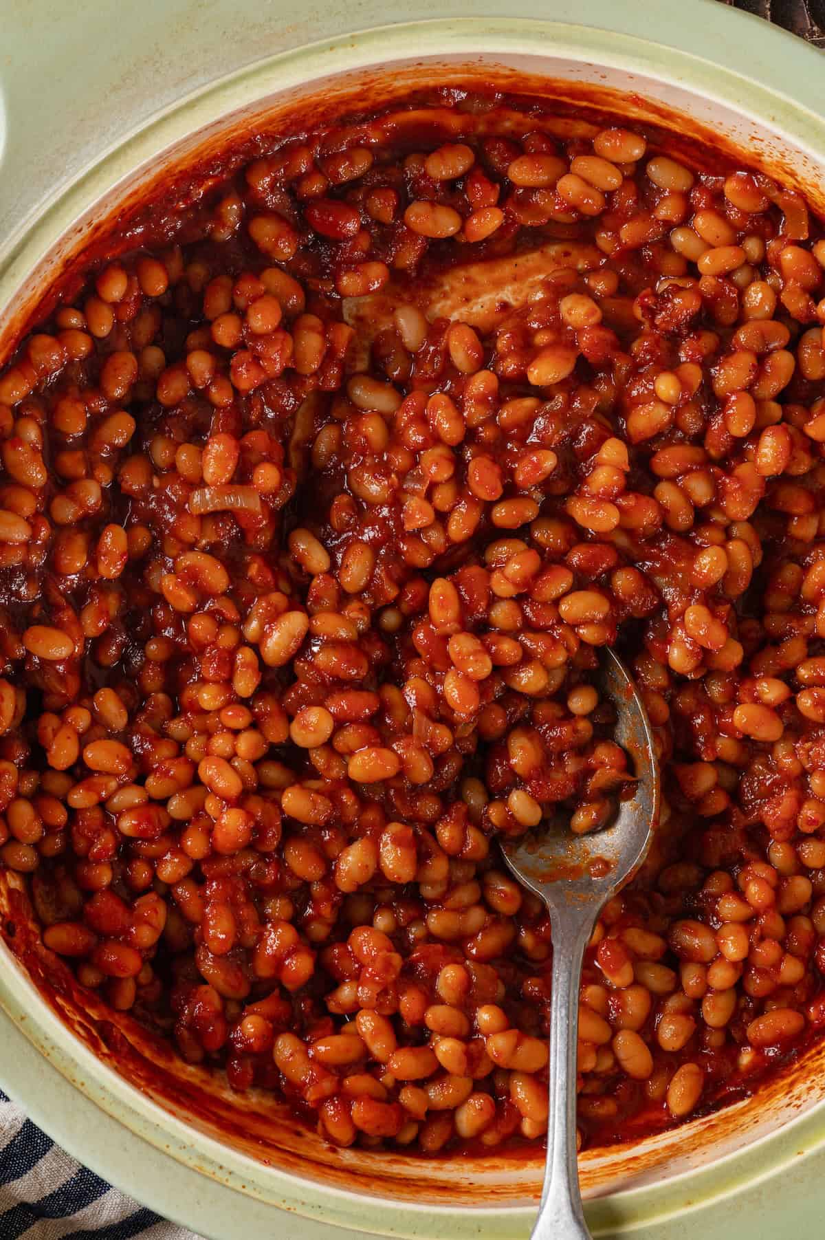 Overhead view of vegan baked beans in pot with spoon