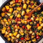 Skillet of vegan breakfast hash with wooden spoon