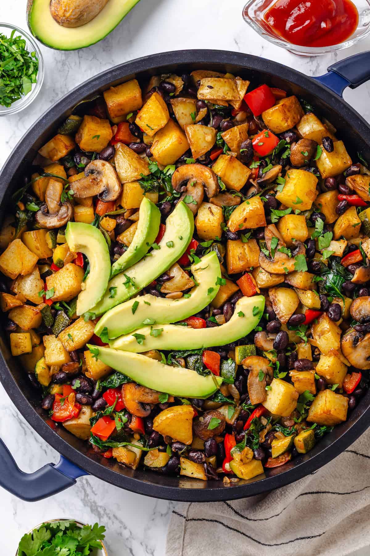 Overhead view of vegan breakfast hash in skillet with avocado slices
