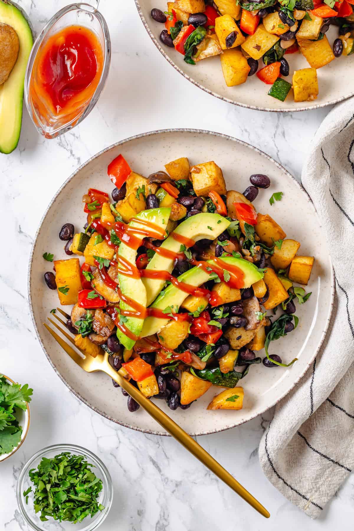 Potatoes are paired with lots of vegetables, black beans, and a smoky seasoning blend for the tastiest, heartiest breakfast hash ever! Overhead view of vegan breakfast hash on plate with fork