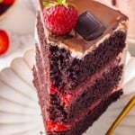 Slice of chocolate strawberry cake on plate with tip on fork