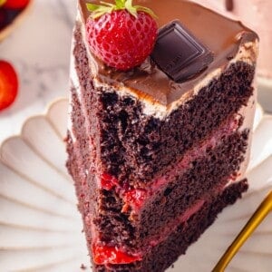 Slice of chocolate strawberry cake on plate with tip on fork