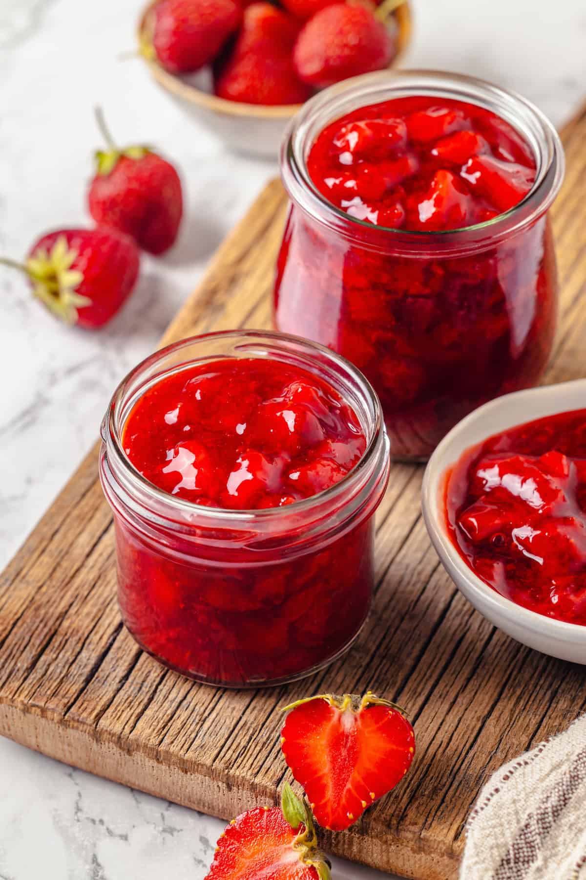 Two jars and bowl of strawberry filling for cake