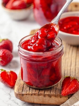 Spoonful of strawberry cake filling held over jar