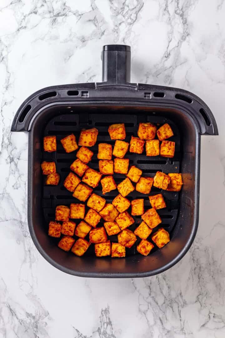 These crispy Tofu Tacos are topped with meaty fajita mushrooms and veggies for a vegan taco recipe that’s satisfying and delicious! Overhead view of air fryer tofu in basket