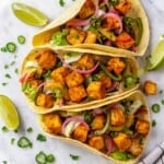 Overhead view of 3 crispy tofu tacos on marble tray