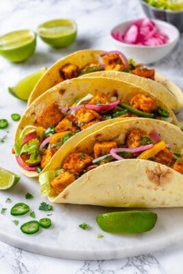 Three tofu tacos lined up on marble tray