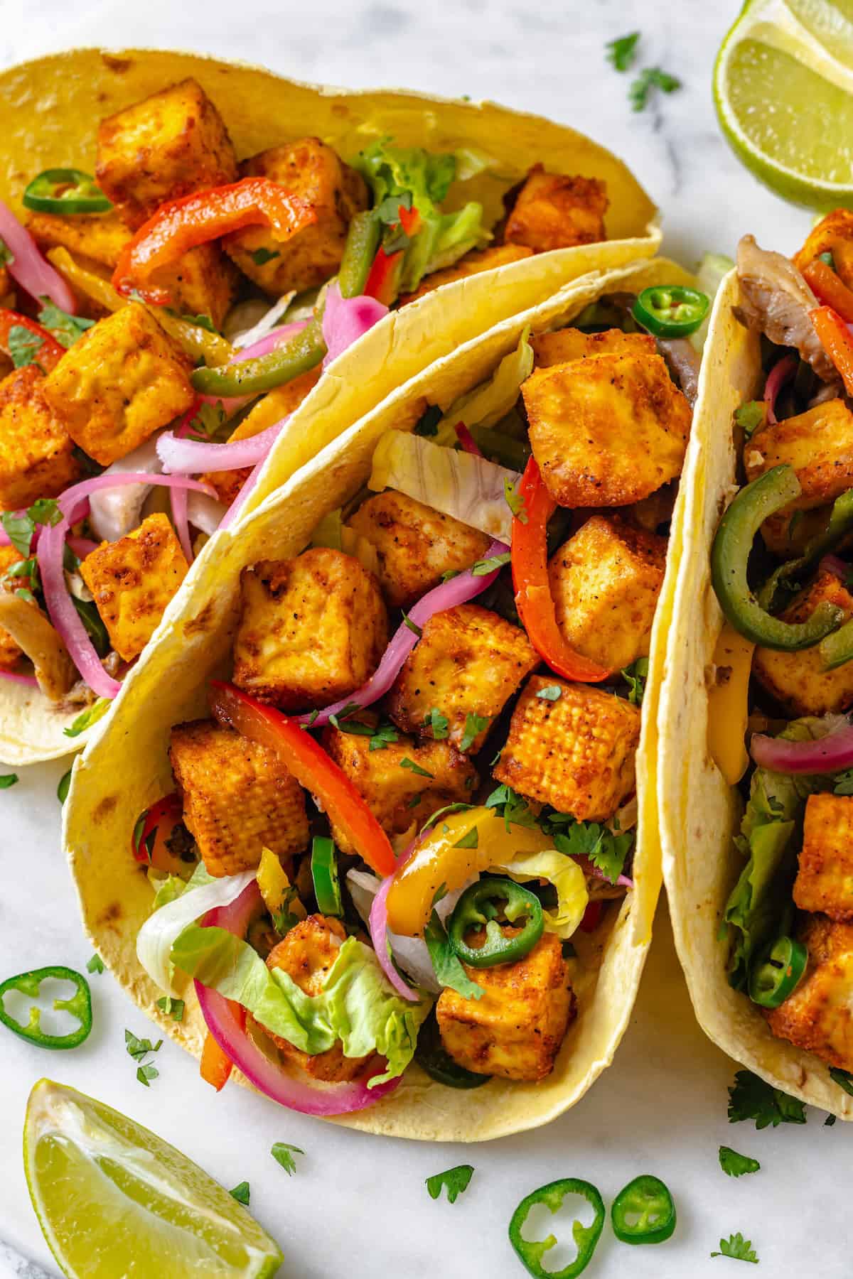 These crispy Tofu Tacos are topped with meaty fajita mushrooms and veggies for a vegan taco recipe that’s satisfying and delicious! 3 tofu tacos with fajita vegetables