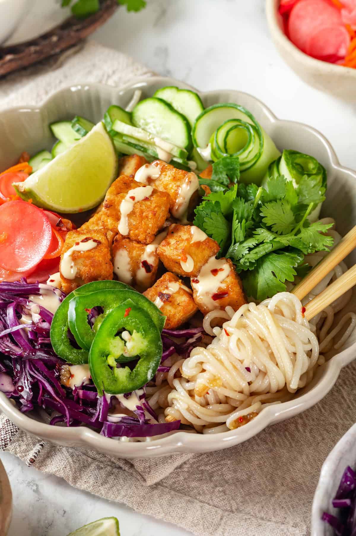 Noodles twirled around chopsticks in vegan banh mi bowl.