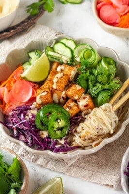 Vegan banh mi bowl with chopsticks tangled in noodles.