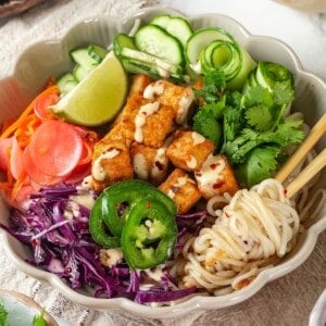 Vegan banh mi bowl with chopsticks tangled in noodles.