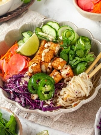 Vegan banh mi bowl with chopsticks tangled in noodles.