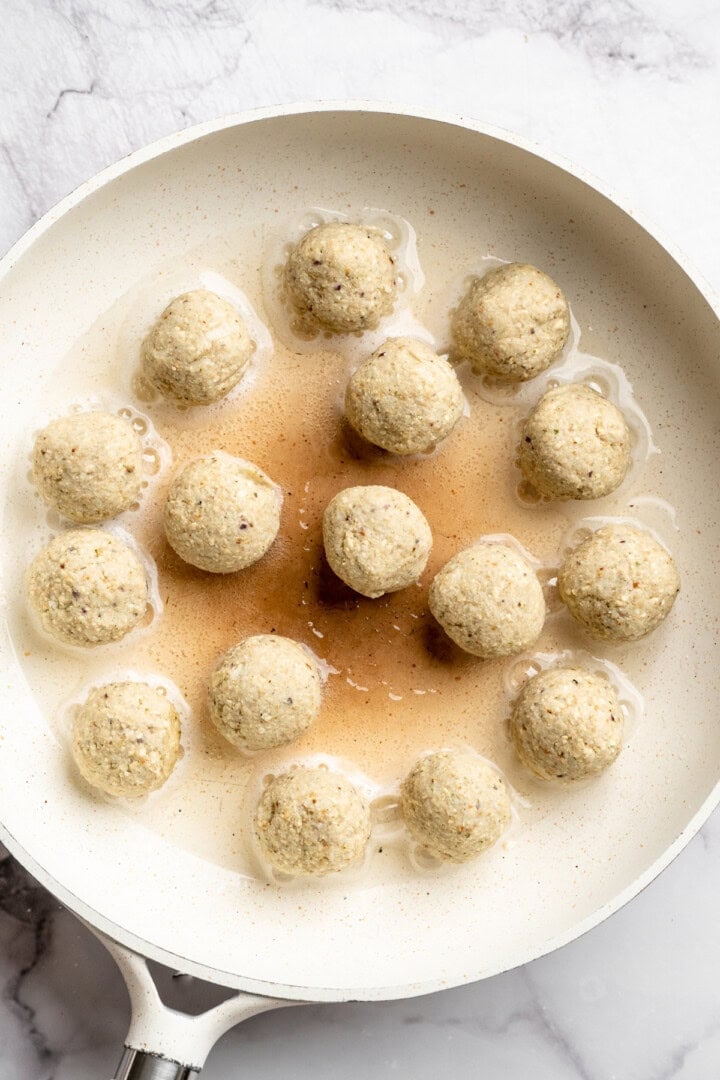 Buffalo cauliflower meatballs cooking in skillet.