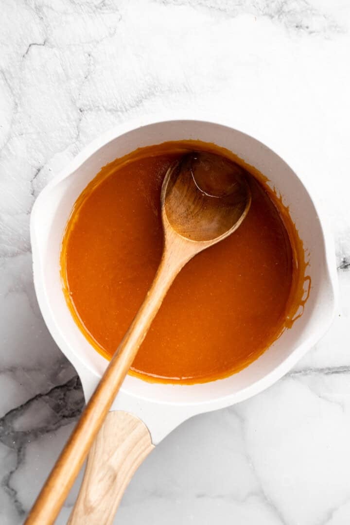 Vegan Buffalo sauce in pan with wooden spoon.