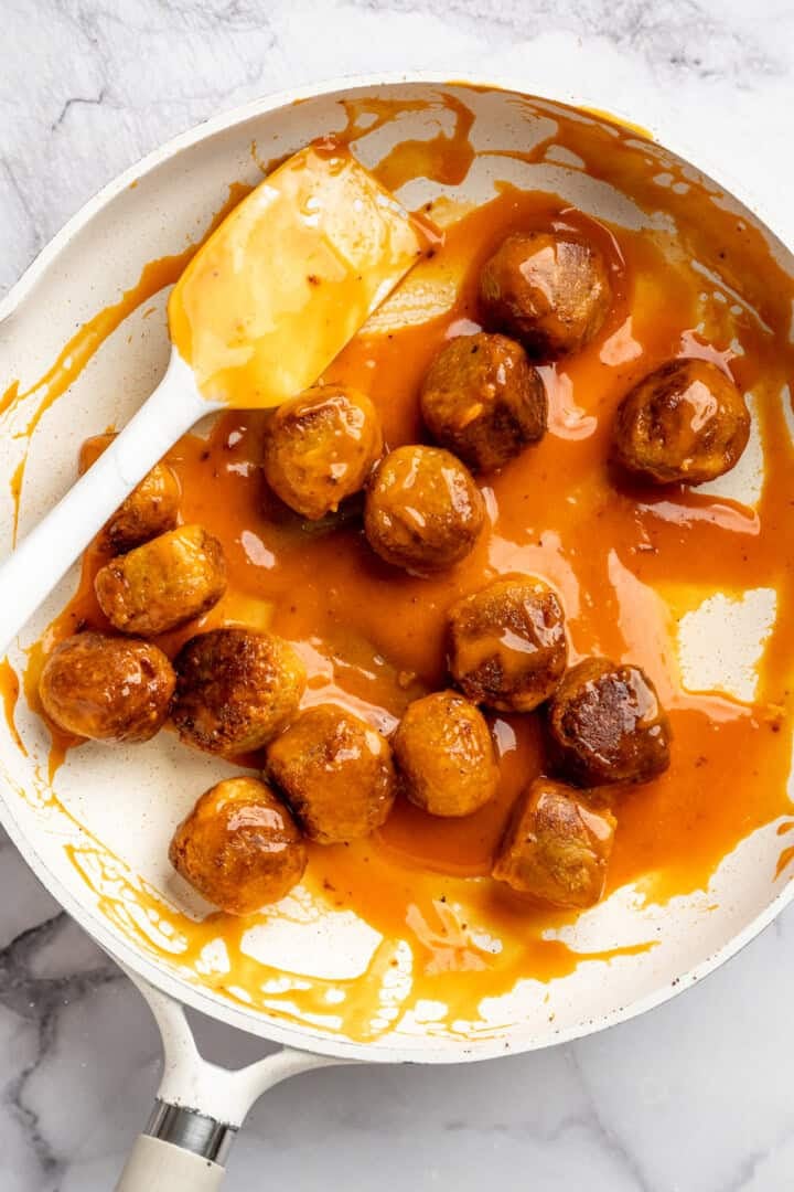 Cauliflower meatballs in skillet with Buffalo sauce.