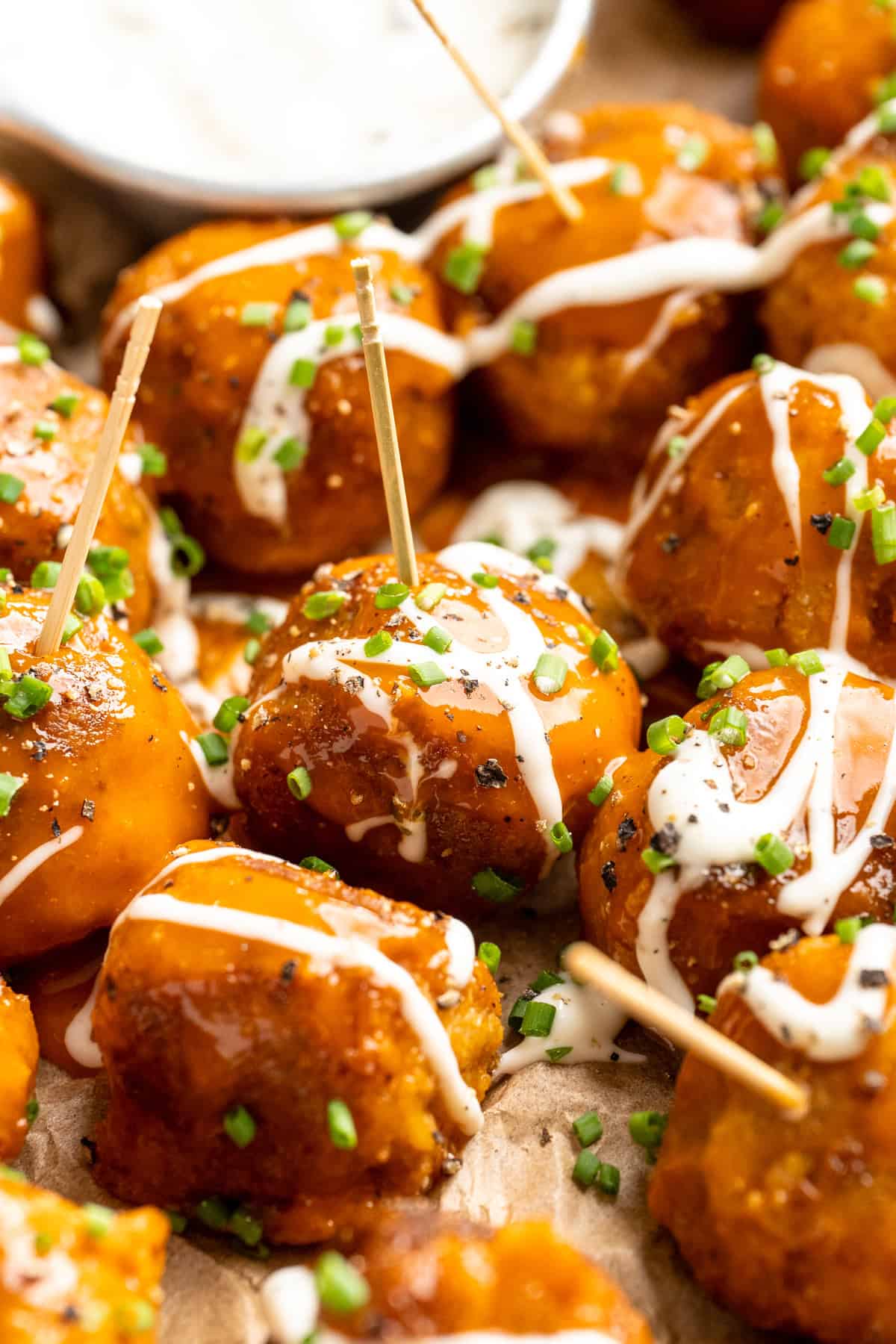 Buffalo cauliflower meatballs on toothpicks with ranch drizzle.